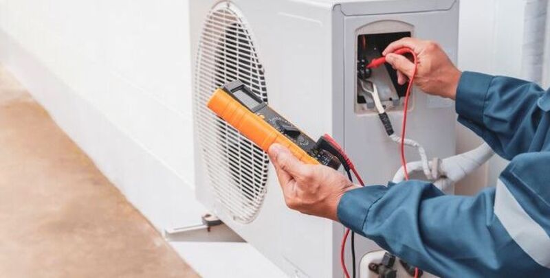 A technician services an air conditioner