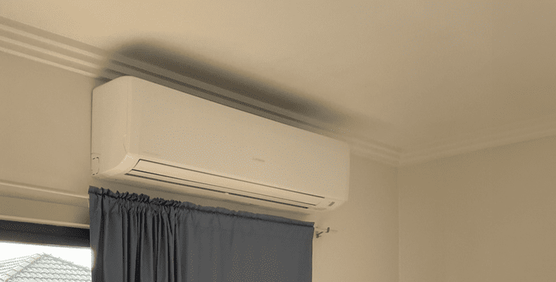 split system indoor unit installed on wall just above blue curtains